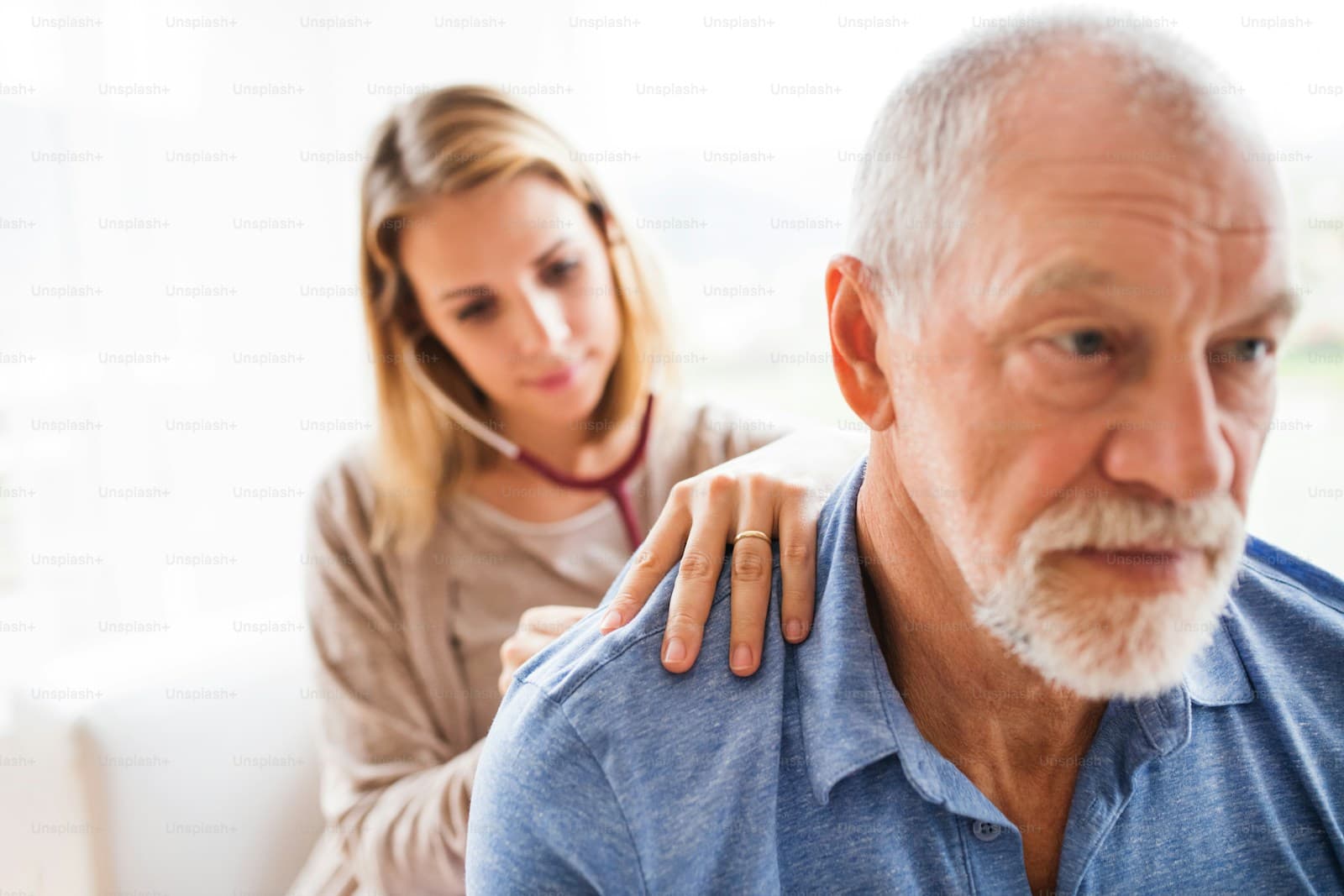 A healthcare worker examining a senior man during a home visit